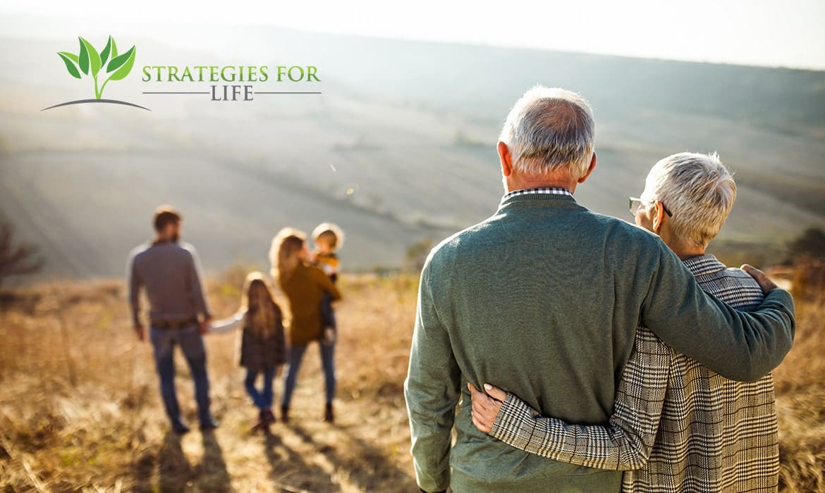 Grandparents looking out towards their younger family members on a hill in the sun